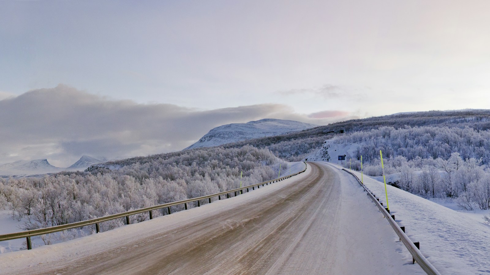 Bil på snötäckt vinterväg i Abisko i Sverige - påminnelse om att skrapa bilrutorna inför körning